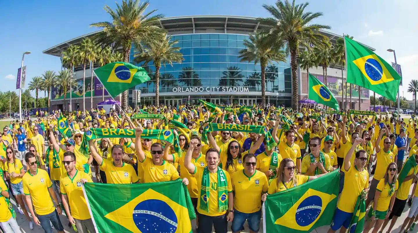Brasilianske fotballfans i gule drakter jubler foran et VM-stadion